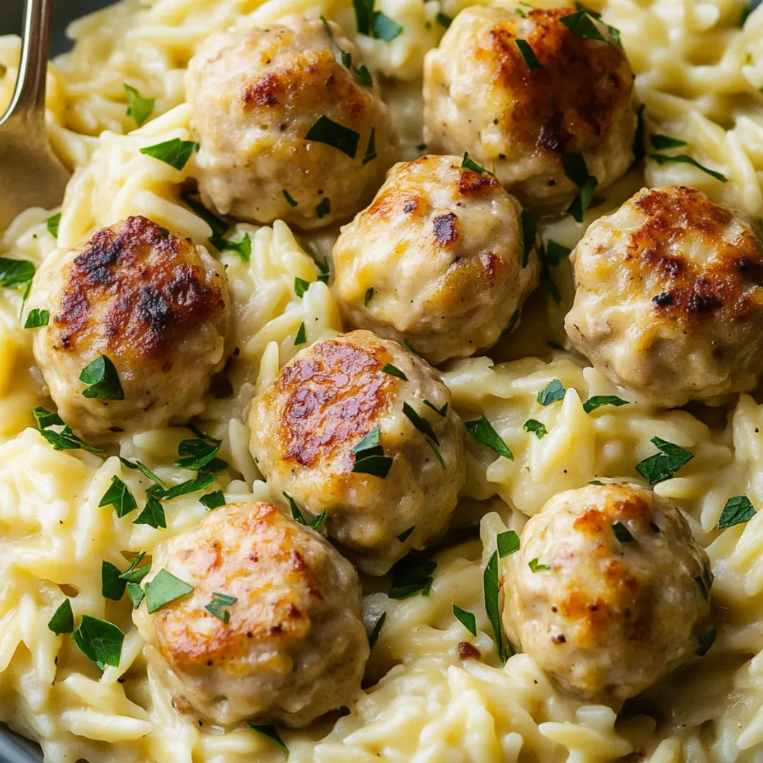 Ein tiefes Schälchen voll mit Pasta, Hähnchenbällchen und Gemüse.