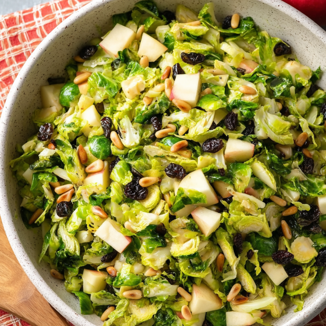 Eine Schüssel mit Salat, Äpfeln, Nüssen und grünem Gemüse.