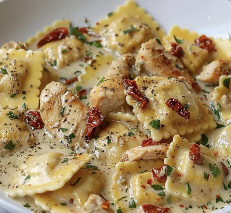Pasta mit Huhn, getrockneten Tomaten und roten Paprikastreifen auf einem Teller.