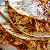 Gestapelte Hähnchen-Quesadilla-Ecken mit Sauce daneben.