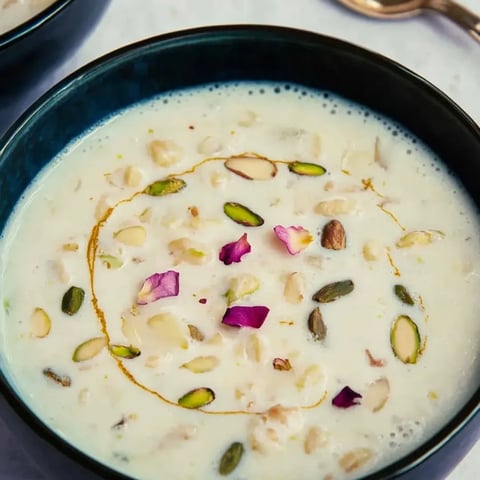 Eine Schüssel Suppe mit Nüssen und Blüten darin.